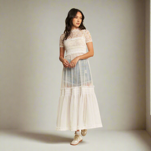 Woman wearing a white lace dress with sheer overlay on a white background